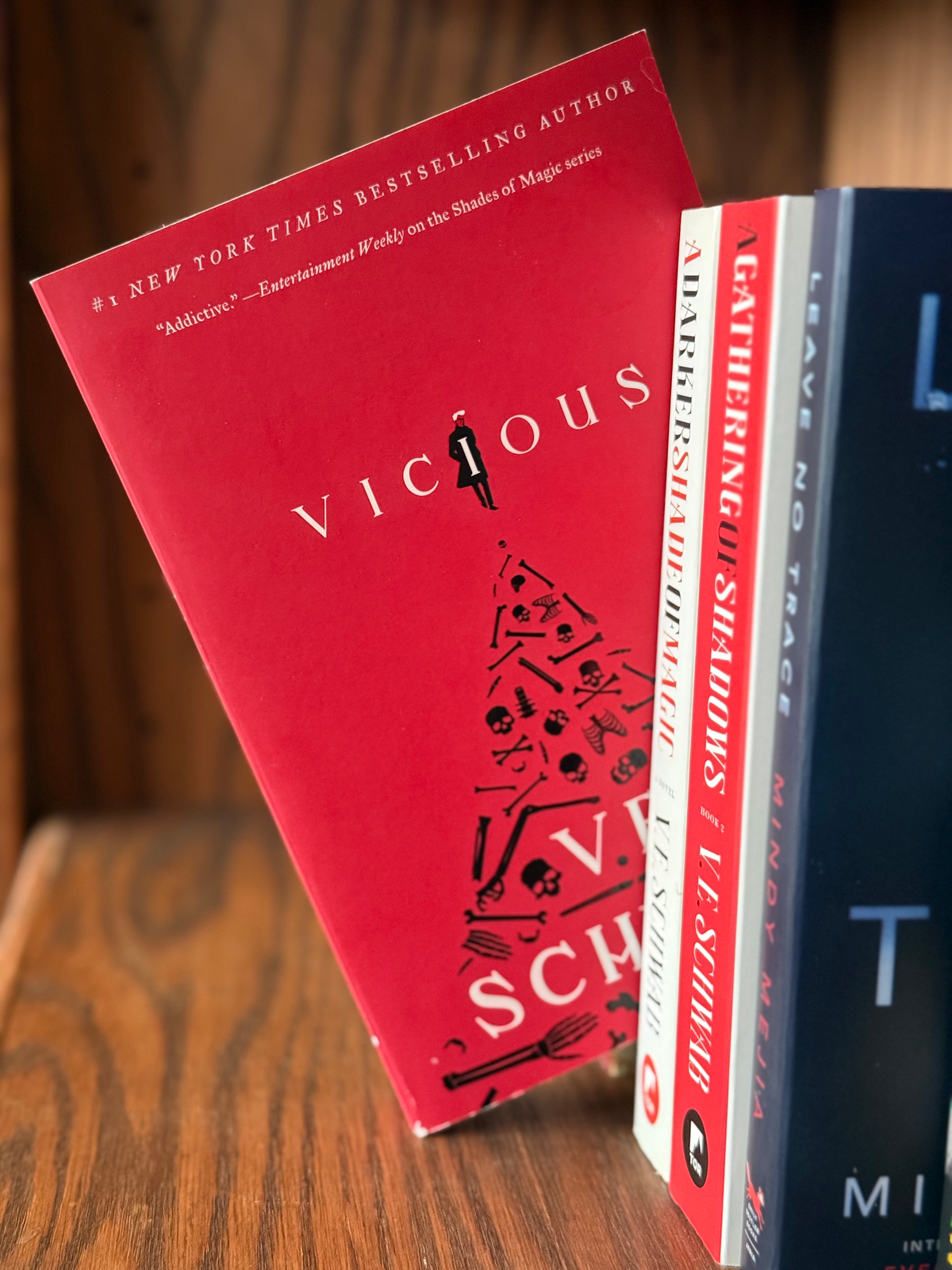 A paperback copy of Vicious by V.E. Schwab sitting on a bookshelf next to other paperback books.