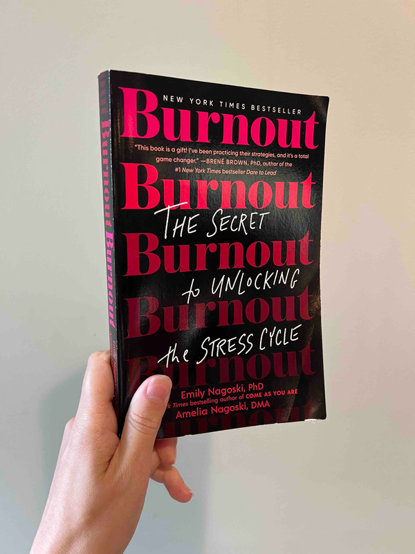 A hand holding up a paperback copy of Burnout by Emily Nagasaki, PhD and Amelia Nagasaki, DMA.